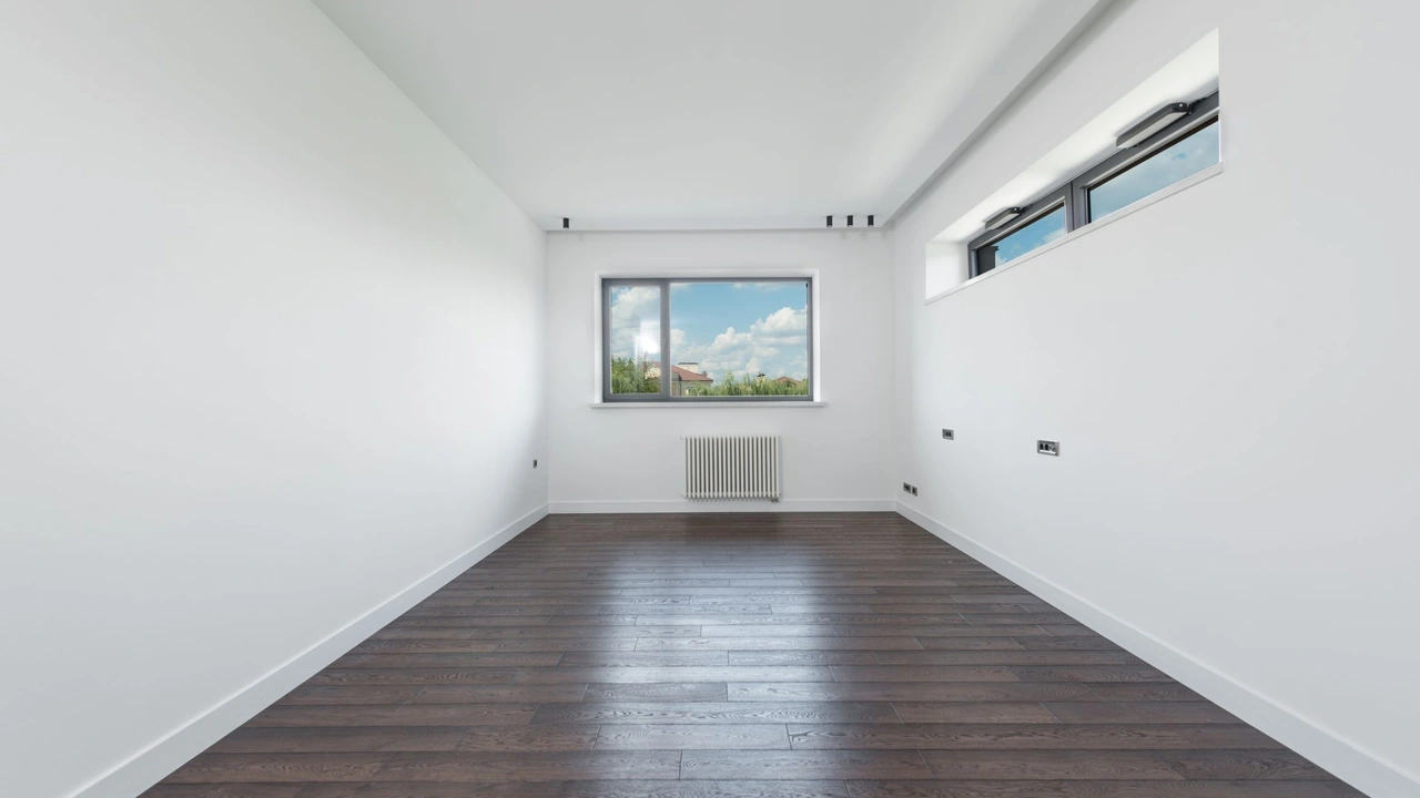 Pièce vide aux murs blancs et au parquet foncé, prête à être habitée